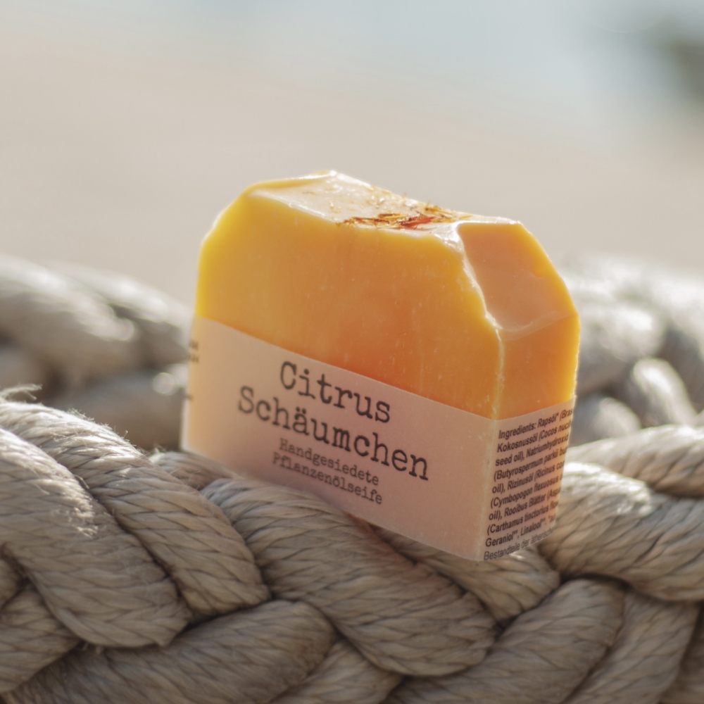 Handgemachte CitrusSchäumchen Naturseife mit frischem Zitrusduft auf einem dicken Tau liegend